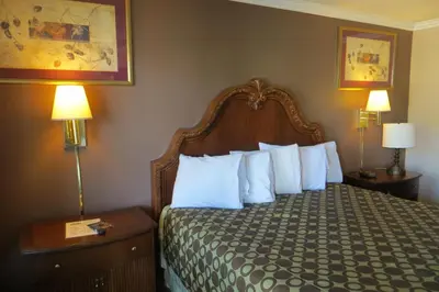 a hotel room with a bed with white pillows at American Inn Stockton in Stockton