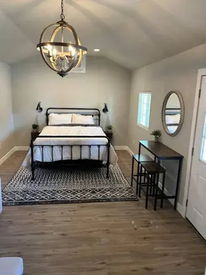 a bedroom with a bed and a table and a chandelier at Adorable One Bedroom Cottage in Oakdale