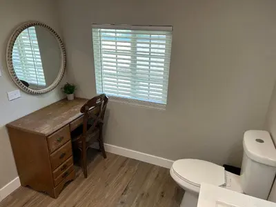 a bathroom with a desk and a toilet and a mirror at Adorable One Bedroom Cottage in Oakdale