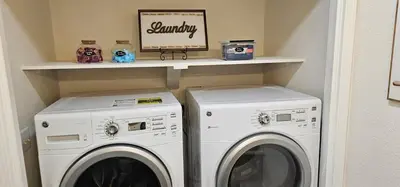 a laundry room with two washing machines and a shelf at Magnolia Peaceful Vibes Cozy Near Hospital in Hanford