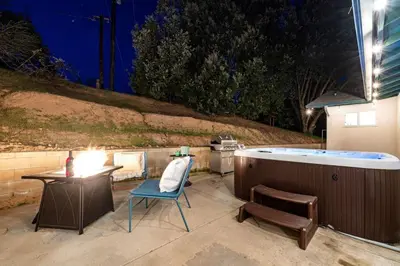 a hot tub sitting next to a table and a chair at Manic Mountain Forest Cabin 3 miles from Bass Lake in Oakhurst