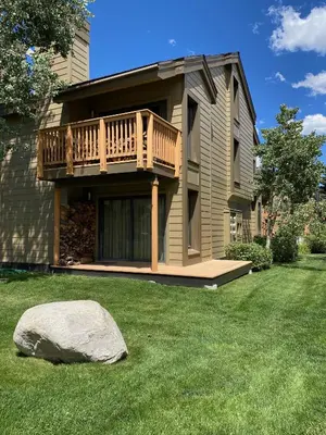 a house with a deck and a rock in the yard at Snowcreek II 2 plus loft 2 bathroom end unit condo sleeping 8 people with amazing mountain view in Mammoth Lakes