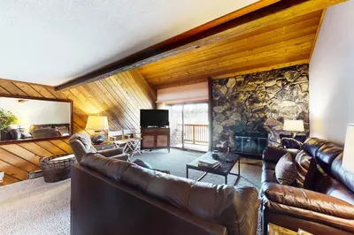 a living room with leather couches and a stone wall at Snowcreek 234 in Mammoth Lakes