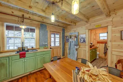 a dining room with a table and a kitchen with wooden walls at Creekside Cabin about 20 Mi to Kings Canyon Park! in Badger