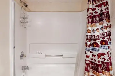 a bathroom with a shower with a christmas shower curtain at Wilts Happy Place in Bass Lake