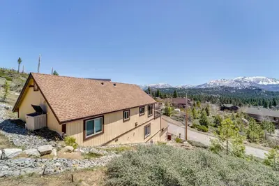 a house on a hill with mountains in the background at Furnished Deck and Gas Grill South Lake Tahoe Home! in South Lake Tahoe