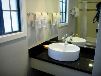 a bathroom with a sink and a mirror at FairBridge Inn & Suites Gateway to Yosemite in Merced