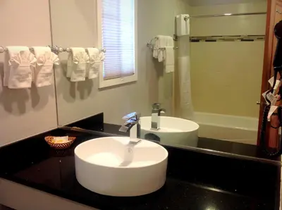 a bathroom with a white sink and a mirror at FairBridge Inn & Suites Gateway to Yosemite in Merced
