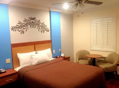 a hotel room with a bed and chairs and a window at FairBridge Inn & Suites Gateway to Yosemite in Merced