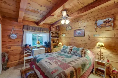 a bedroom with a bed in a log cabin at Creekside Cabin By Calaveras Big Trees State Park in Camp Connell