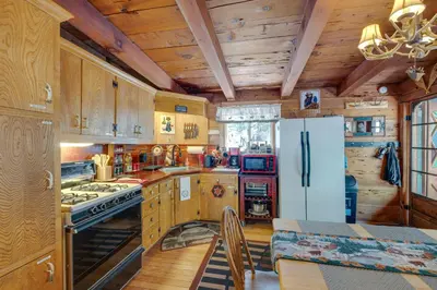 a kitchen with wooden cabinets and a refrigerator at Creekside Cabin By Calaveras Big Trees State Park in Camp Connell