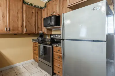 a stainless steel refrigerator in a kitchen with wooden cabinets at Tyrolean Village 6 2 Bedroom 1 and a Half Bath Sleeps 6 Walk to Lift Steps to town shuttle in Mammoth Lakes
