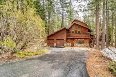 a large wooden house in the woods with a driveway at Deck with Hot Tub Serene Cabin in Truckee in Truckee