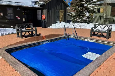 a blue swimming pool with two chairs and snow at Lodges 1136 in Mammoth Lakes