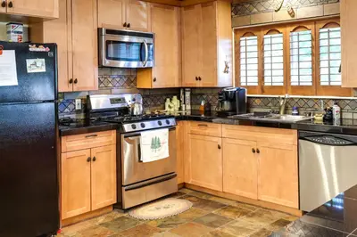 a kitchen with wooden cabinets and a black refrigerator at Cozy Mi-Wuk Village Cabin with Deck! in Mi-Wuk Village