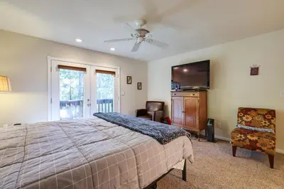 a bedroom with a bed and a television and a chair at Cozy Mi-Wuk Village Cabin with Deck! in Mi-Wuk Village