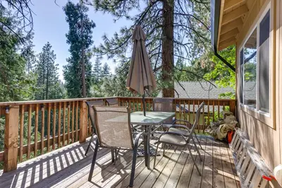 a deck with a table and chairs and an umbrella at Cozy Mi-Wuk Village Cabin with Deck! in Mi-Wuk Village