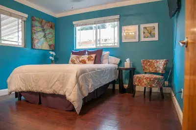 a bedroom with blue walls and a bed and a chair at Sequoia Basecamp with Hot Tub Oasis in Visalia