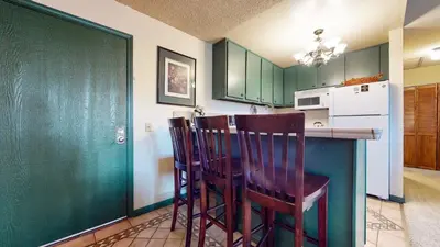 a kitchen with green cabinets and two wooden chairs at Summit #232 condo in Mammoth Lakes