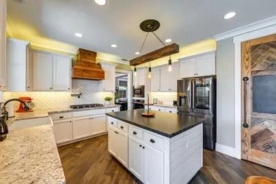 a kitchen with white cabinets and a black counter top at California Vacation Rental with Private Pool and Patio in Visalia