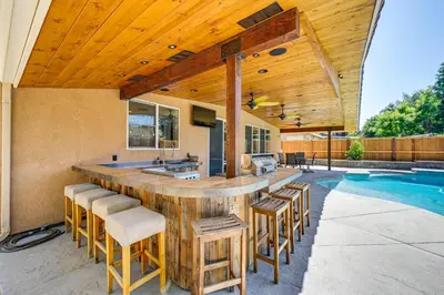 an outdoor kitchen with a bar and a swimming pool at California Vacation Rental with Private Pool and Patio in Visalia
