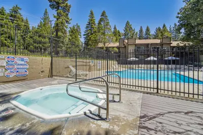 a hot tub in a fence next to a pool at 10 Mi to Palisades Tahoe! Condo with Game Room in Tahoe City