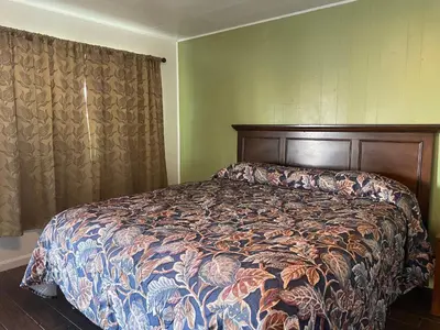 a bedroom with a bed with a floral comforter at Oak Motel Modesto CA in Modesto