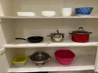 a kitchen shelf with pots and pans and bowls at Brand-New, Beautiful & Stylish Home in Sacramento! in Sacramento