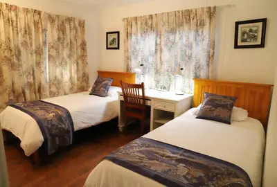 a room with two beds and a desk and a table at Green Cabin in Midpines in Midpines