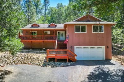 a red house with a white garage and a flag at Groveland Vacation Rental Near Pine Mountain Lake! in Groveland