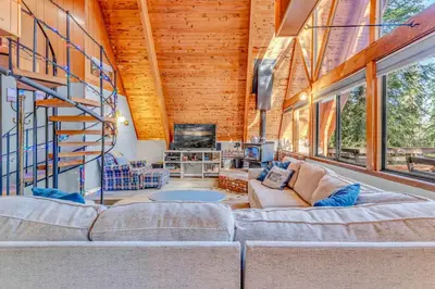 a living room with a couch and a staircase at 3BR Tahoe Cabin in the Trees with Hot Tub in Carnelian Bay