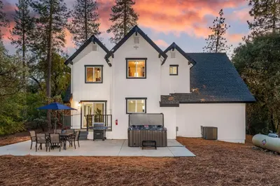 a white house with a table and chairs at A Modern Hideaway - with hot tub, game room, and more in Oakhurst