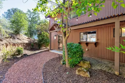 a house with a tree and a gravel driveway at Yosemite Sunrise House with hot tub/views/game room in Oakhurst