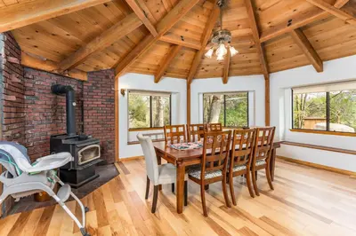 a dining room with a table and chairs and a wood stove at Sunset Retreat- TWO houses with hot tub, firepit, multiple kitchens, sleeps 20 in Coarsegold