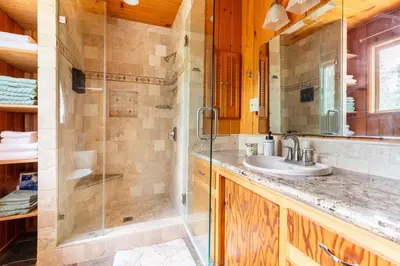 a bathroom with a shower and a sink and a mirror at Sequoia Retreat- Spacious Cabin, Hot tub, & Sundeck in Ponderosa