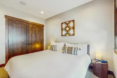 a bedroom with a white bed and a wooden cabinet at Red Mountain Lodge in Truckee