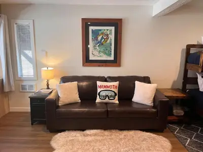 a living room with a brown leather couch with pillows at Cozy Ski Condo - Walk to Canyon - Dog Friendly in Mammoth Lakes