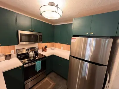 a kitchen with green cabinets and a stainless steel refrigerator at Cozy Ski Condo - Walk to Canyon - Dog Friendly in Mammoth Lakes