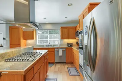 a kitchen with wooden cabinets and a stainless steel refrigerator at Near Dtwn Twain Harte Home with Furnished Deck! in Twain Harte