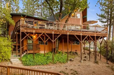 a large wooden house with a wrap around deck at Bass Lake Lodge in Bass Lake