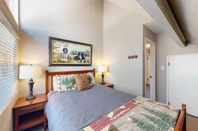 a bedroom with a bed and a table with a lamp at Bass Lake Lodge in Bass Lake