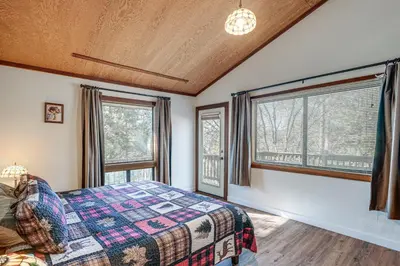 a bedroom with a bed and two windows at Deck and Gas Grill Secluded Arnold Cabin Rental! in Arnold