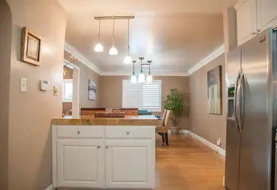 a kitchen with white cabinets and a stainless steel refrigerator at Group Retreat with Hot Tub & Studio in Visalia