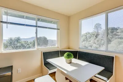 a dining room with a white table and chairs and windows at Comfy Oakhurst Duplex Near Hiking and Sightseeing! in Oakhurst