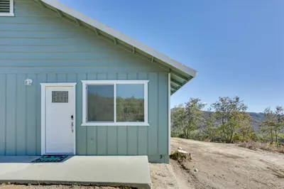 a green house with a door and a window at Comfy Oakhurst Duplex Near Hiking and Sightseeing! in Oakhurst