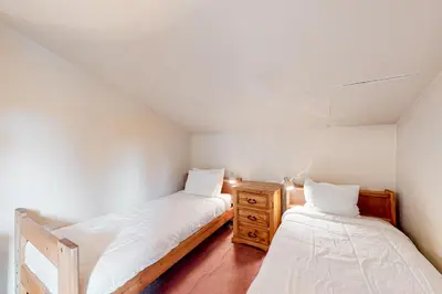 two beds in a small room with a wooden dresser at Crestview 70 in Mammoth Lakes