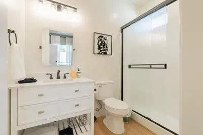 a white bathroom with a toilet and a shower at Reno Dream Cottage: Delightful 2-Bedroom Sanctuary in Reno
