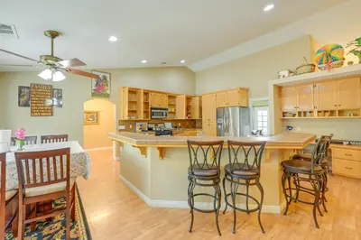 a kitchen with wooden cabinets and bar stools at Porterville Getaway with Patio and Valley Views! in Porterville