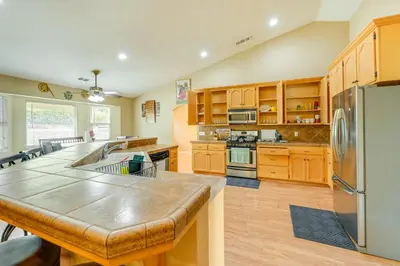 a large kitchen with wooden cabinets and stainless steel appliances at Porterville Getaway with Patio and Valley Views! in Porterville