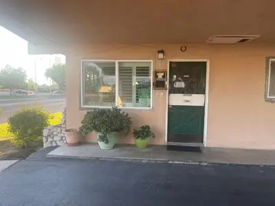 a building with a green door and two potted plants at Town House Motel in Sanger